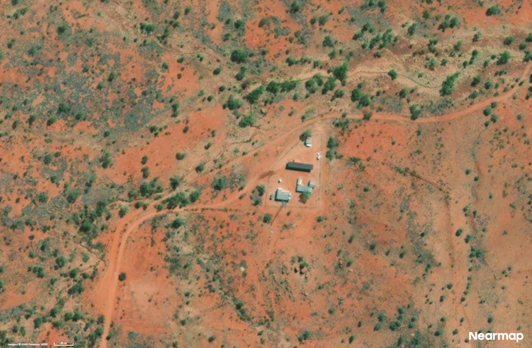 Aerial photo showing buildings in a red, scrubby landscape.