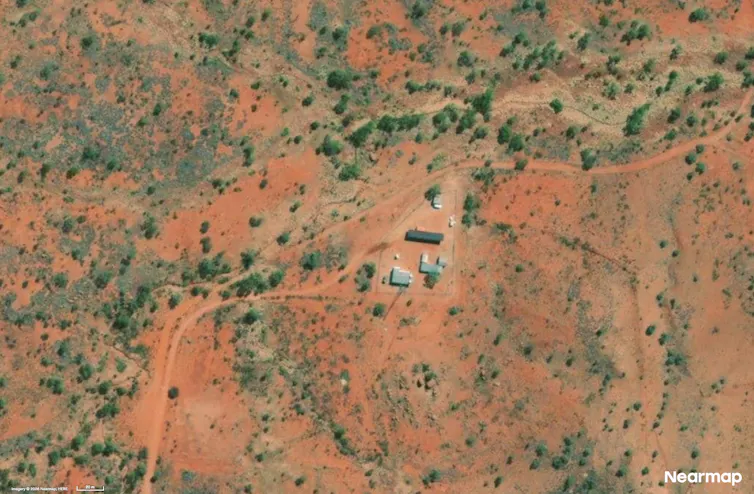 Aerial photo showing buildings in a red, scrubby landscape.