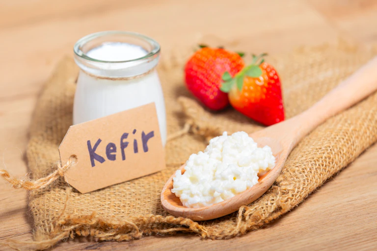 Kefir presentado en un envase de cristal y una cuchara de madera.