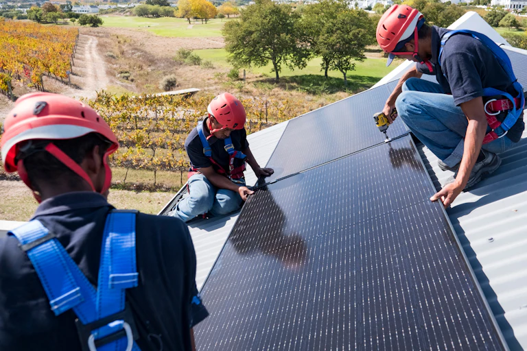 Three workers on a roof of a house fitting a solar panel