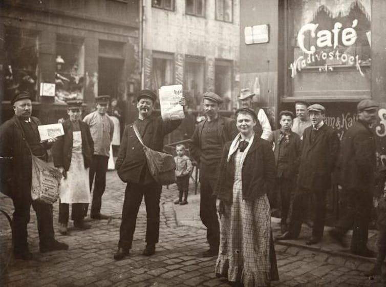 Black and white photo of people standing on the street.