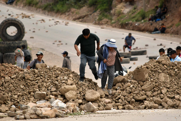 People walk along a blocked road in Bolivia.