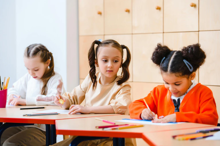 Una niña mira a otra de reojo lo que escribe en un aula.