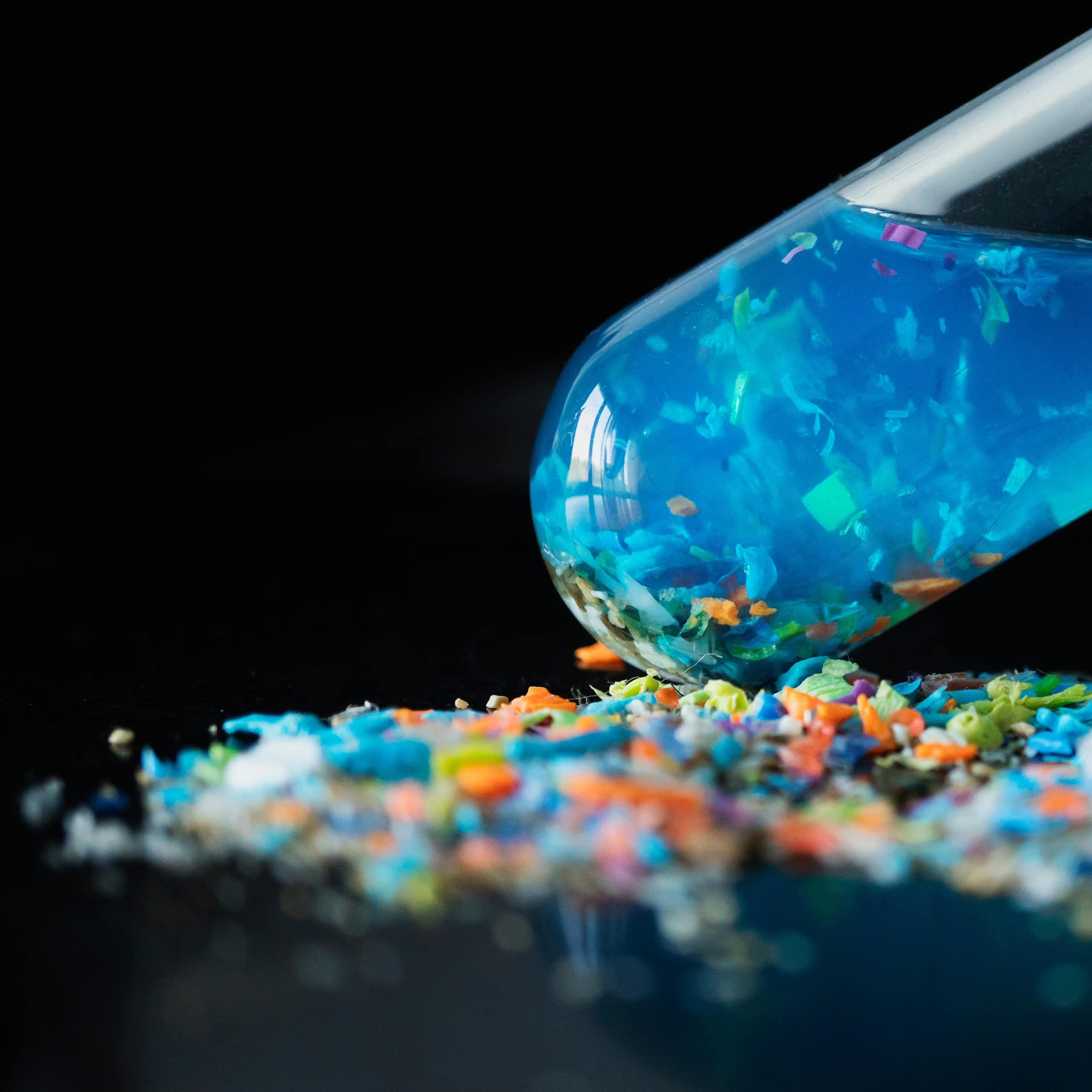 Una proveta amb líquid blau on suren plàstics molt xicotets