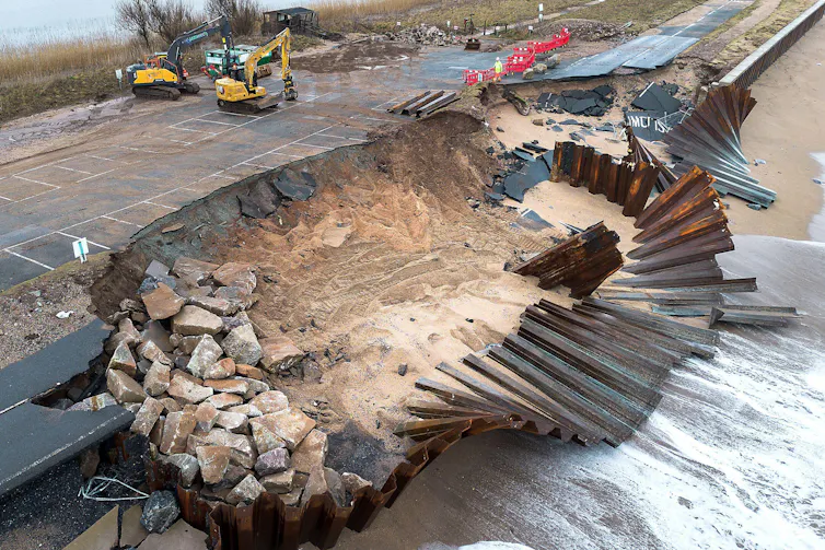 broken road and sea defence, digger in background