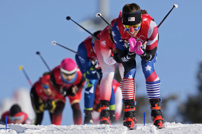 A row of female skiers races down a slope