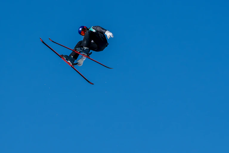 skier in mid air against a bright blue sky.