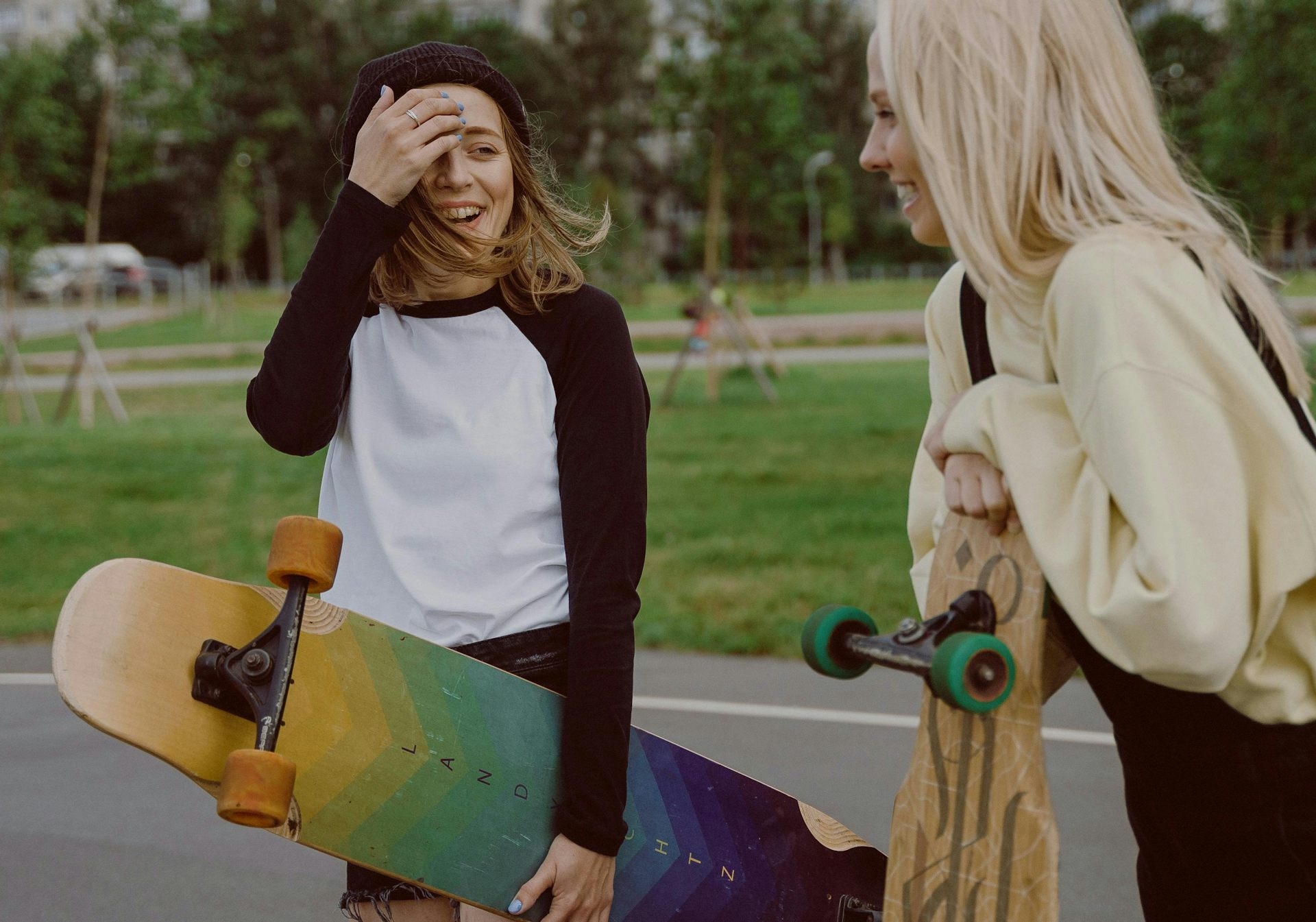 Two teens standing and laughing, one of whom is holding a skateboard.