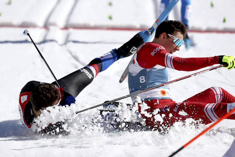 Two male skiers on tangled on the ground after a crash.
