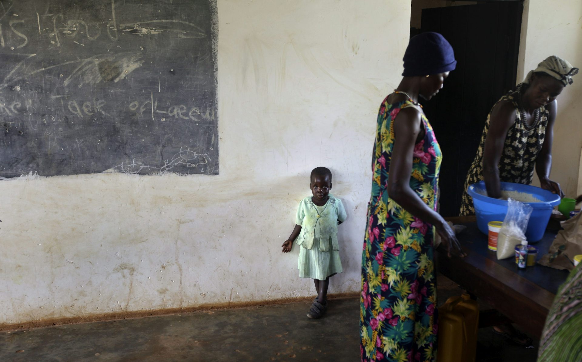 Two women and a young girl standing in a kitchen completing chores.