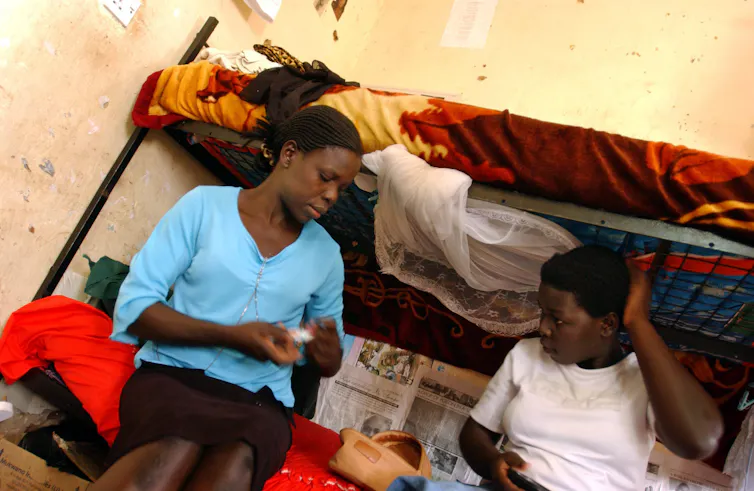 A woman and a child sitting on the lower bed of a bunk bed.