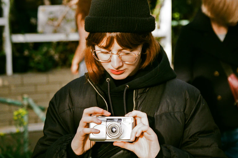 A young woman looks down at a camera held in her hands