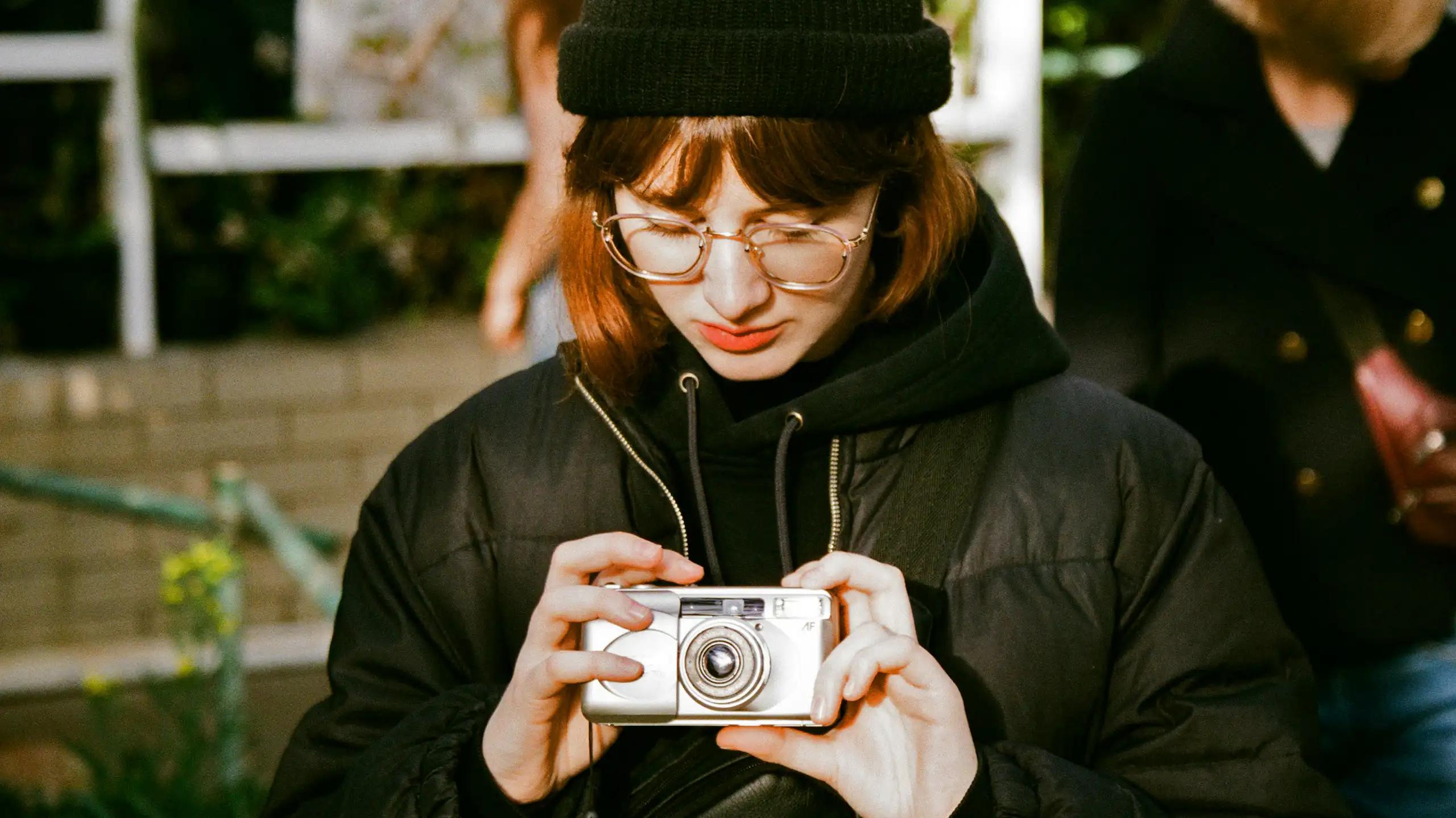 A young woman looks down at a camera held in her hands