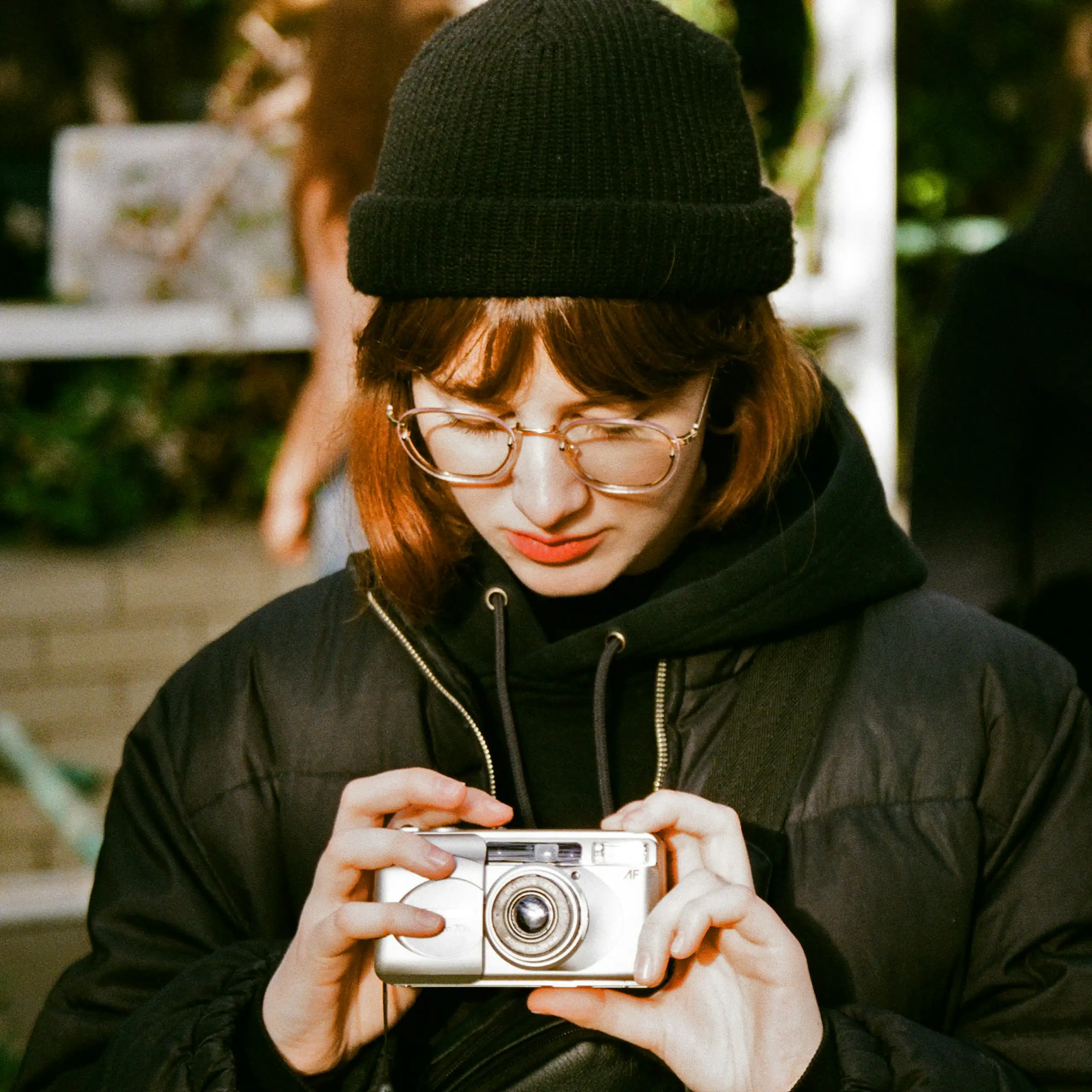 A young woman looks down at a camera held in her hands