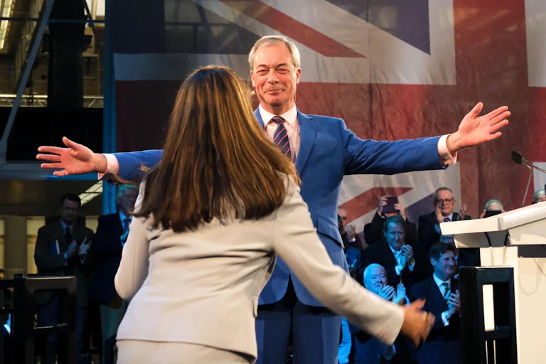 NIgel Farage holding out his arms as Suella Braverman runs towards him to embrace.