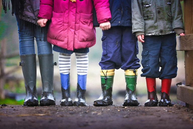 Four children standing on dirt during daytime.