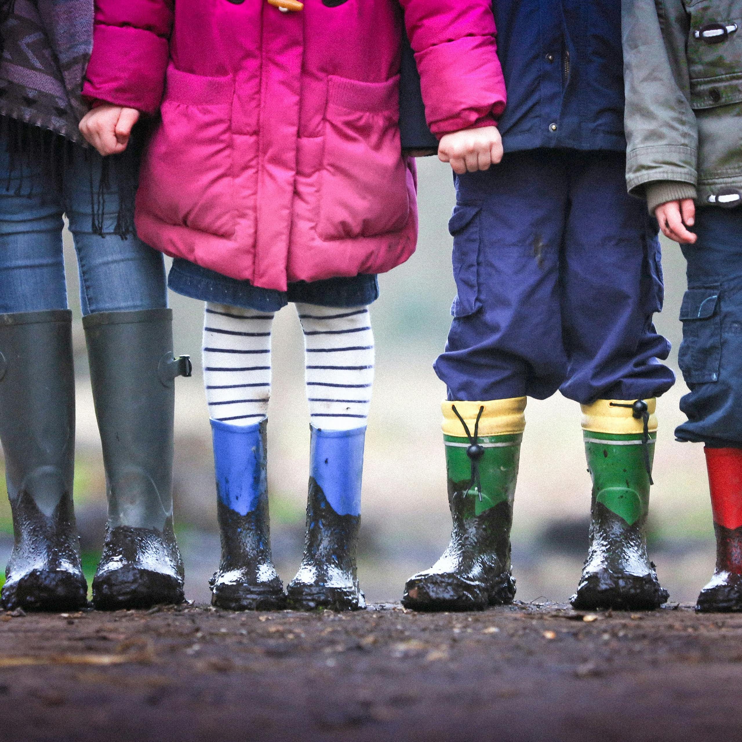 Four children standing on dirt during daytime.
