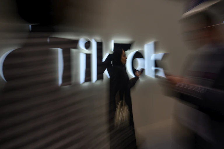 a woman walks by a lighted coprorate logo on a wall