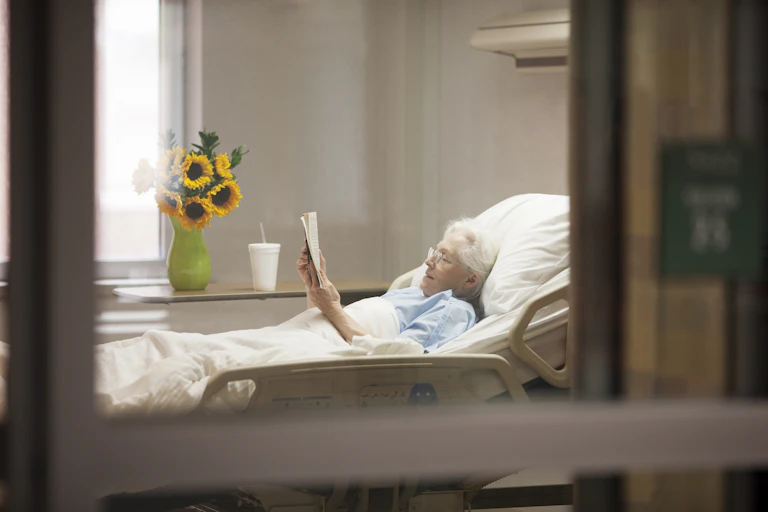 Older woman reads in hospital bed