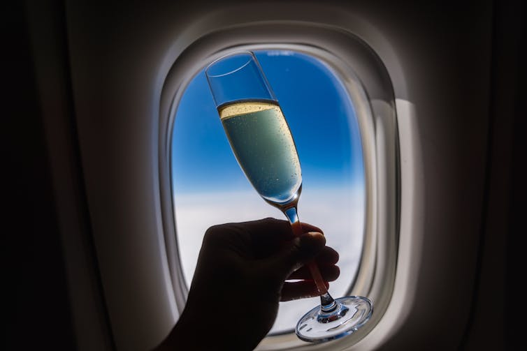 airplane window, hand holding glass of champagne