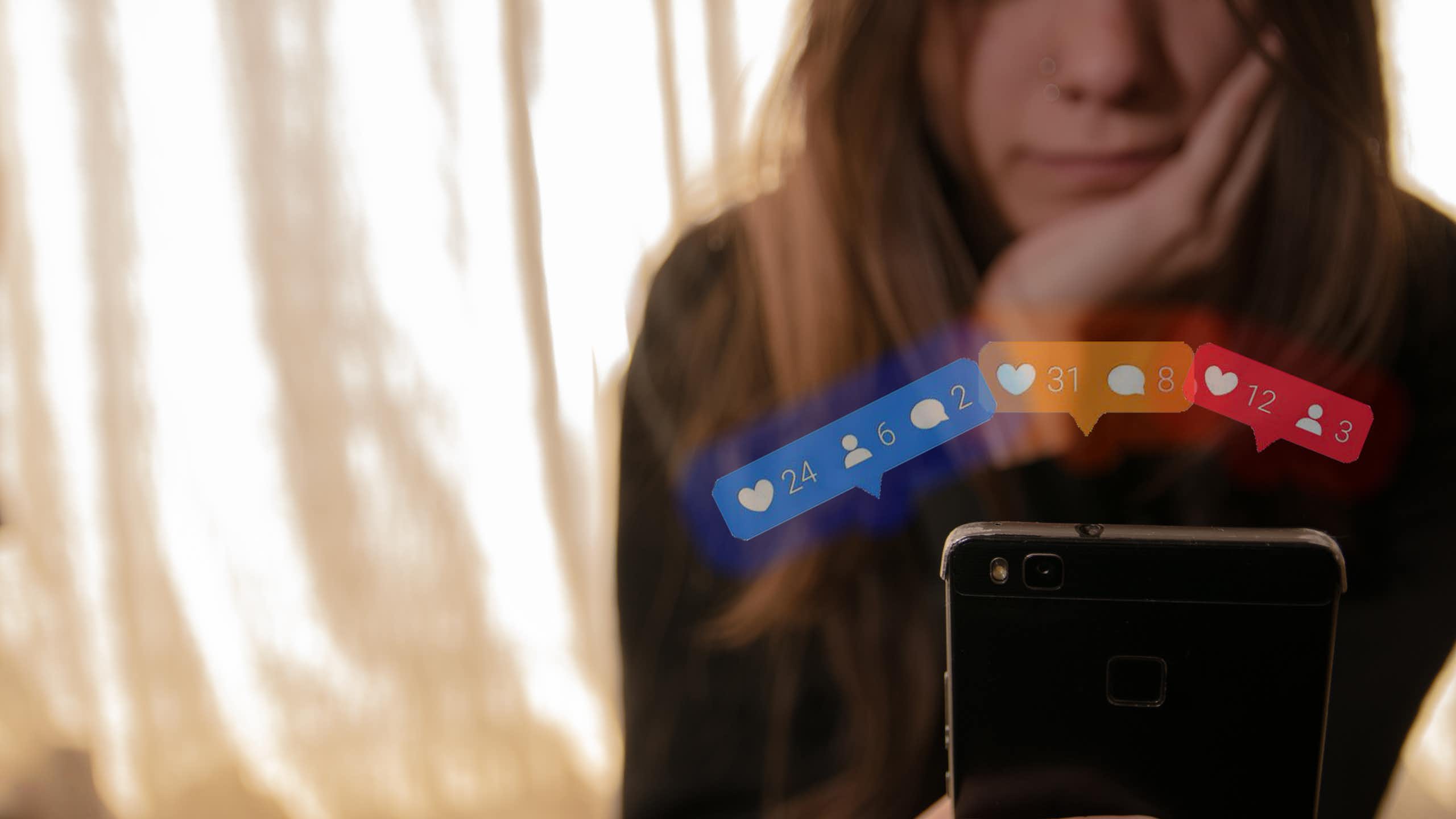 Una adolescent mira la pantalla d'un mòbil