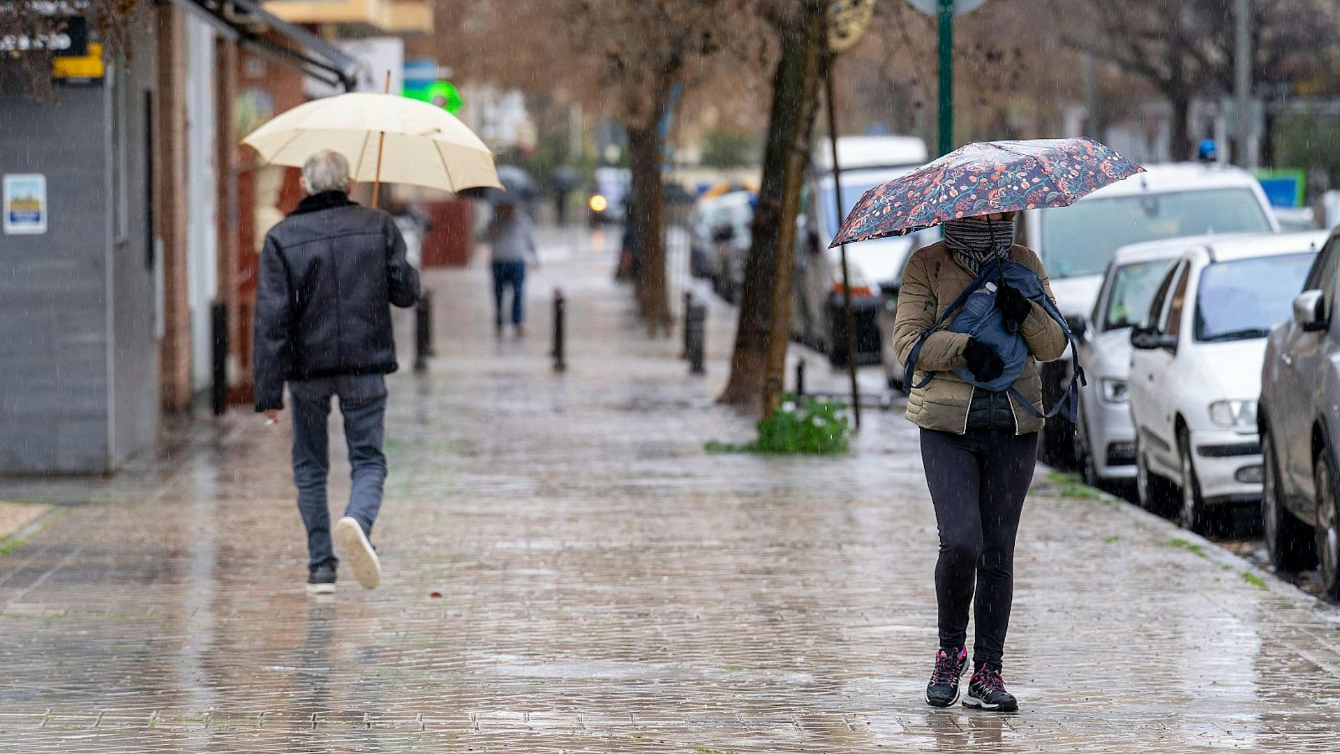 Personas caminan por una calle sujetando paraguas para protegerse de las lluvias