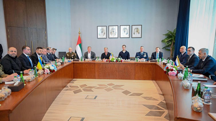 Officials sit around tables making up three sides of a square.