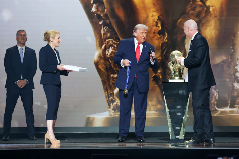 Two men in suits stand on a stage.