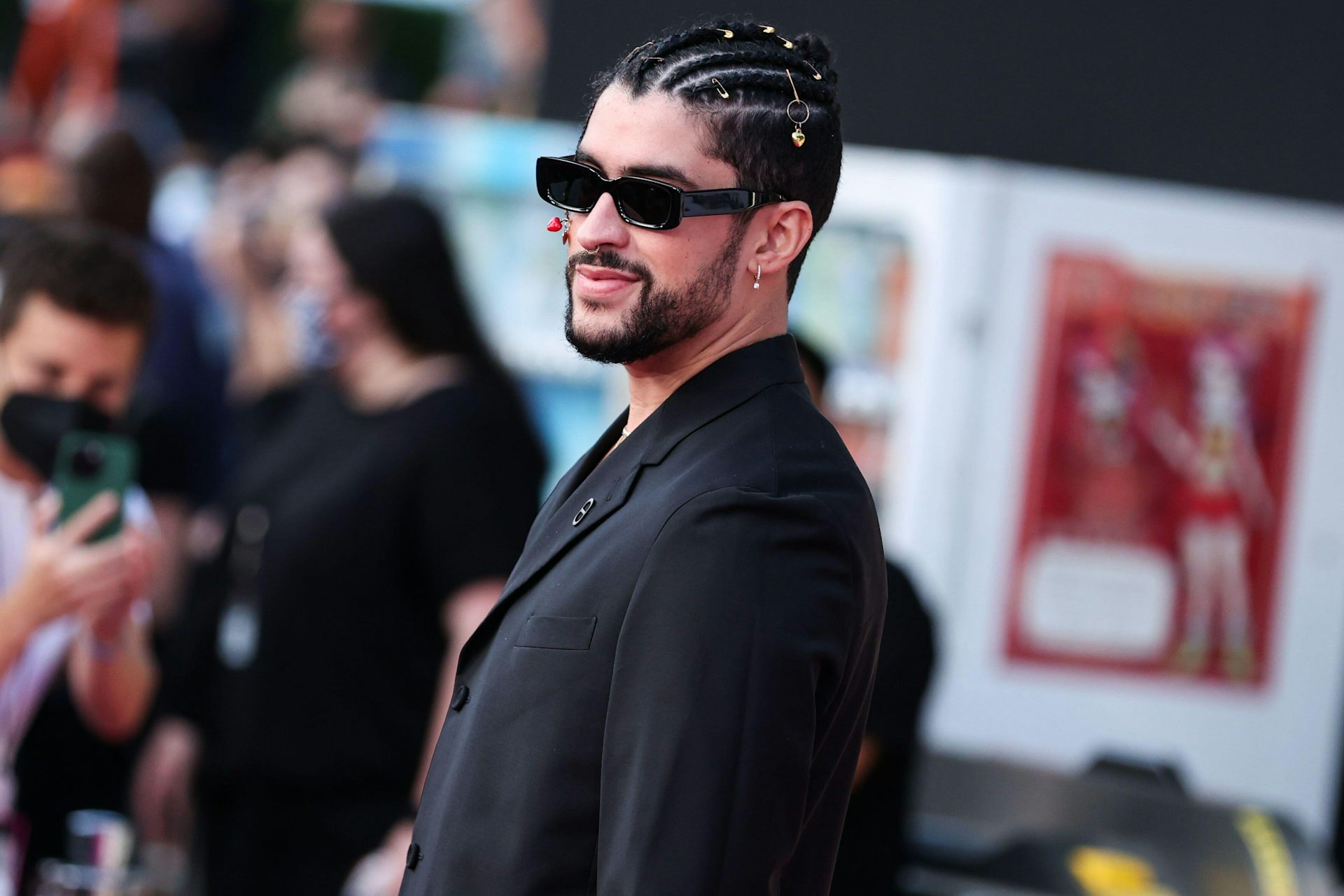 A young man in sunglasses with cornrows in his hair.