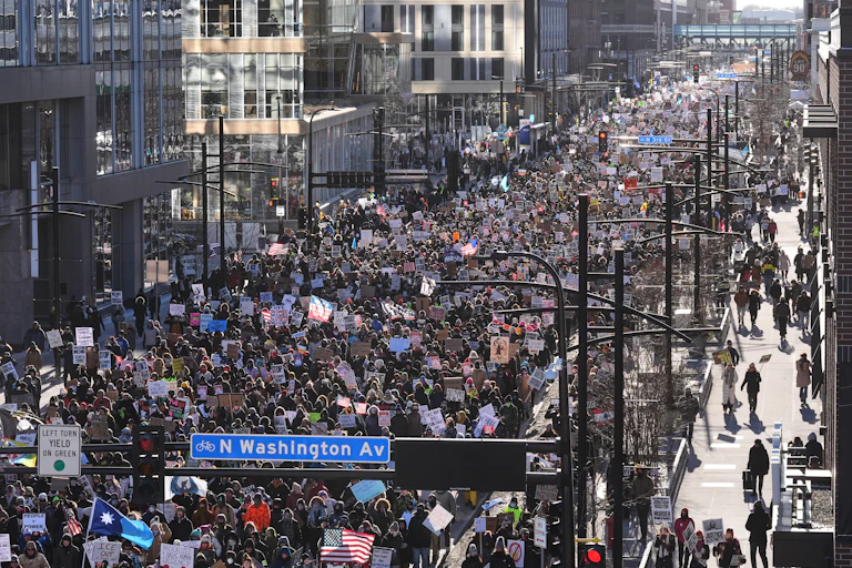 A sea of protesters walk on a city street.