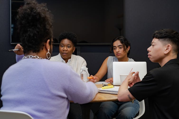 A group of Black and racialized co-workers of varying genders having a meeting.