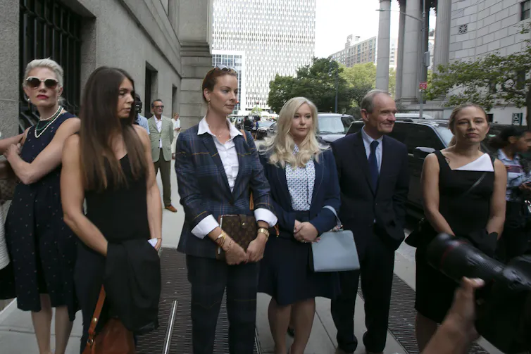 Five women and one man, their lawyer, side by side on a New York street