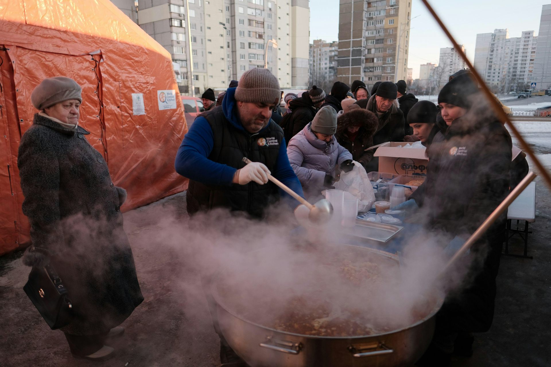 People crowd around a man serving up hot soup on a street in Kyiv, Febriary 2026.