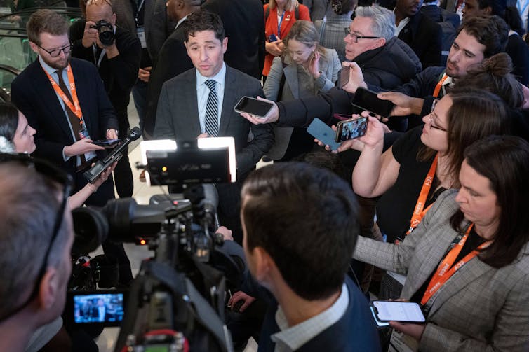 A large group of reporters surround Minneapolis Mayor Jacob Frey.