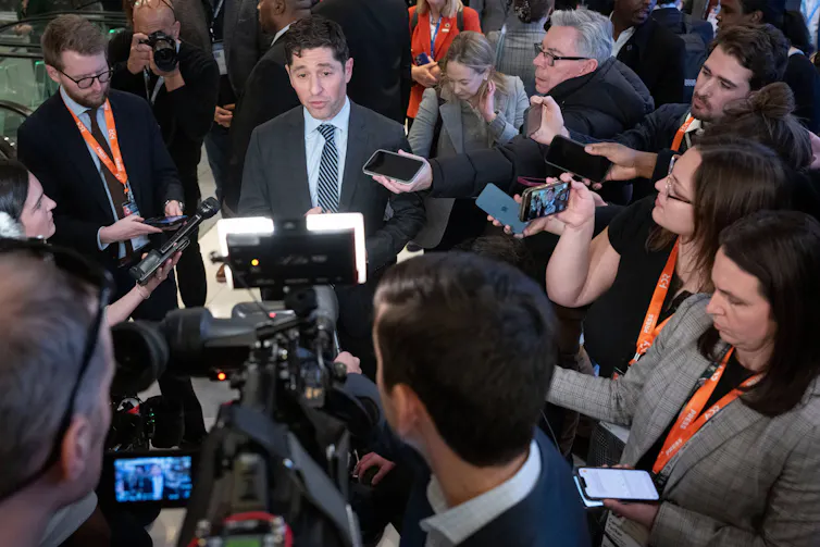 A large group of reporters surround Minneapolis Mayor Jacob Frey.