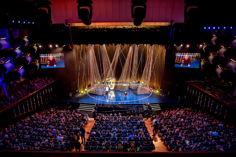 awards stage in theatre packed with people, bright lights