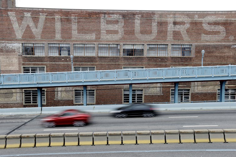 Philadelphia used to be as soon as a candy spot for chocolatiers and different candymakers who made iconic treats for Valentine’s Day and different vacations 3 Cars on highway pass a large brick building with faded paint that reads 'Wilbur's'