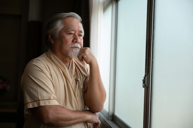 Comprender la diferencia entre apatía y depresión puede salvar la vida de personas con trastornos cerebrales 1 Un hombre con pelo gris y barba gris mira pensativamente por la ventana