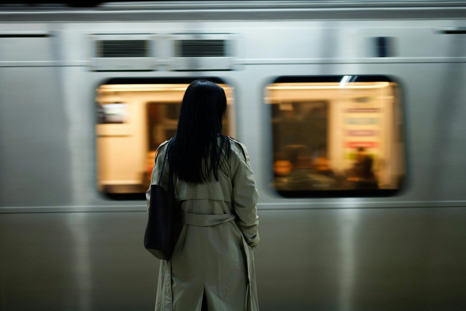 Una mujer con abrigo se encuentra en el andén mientras el tren llega.