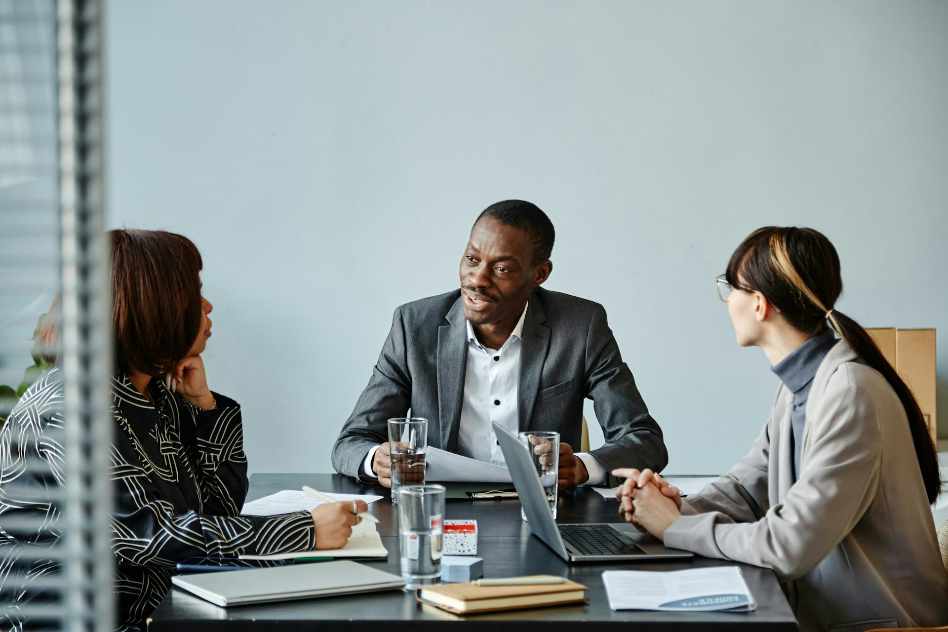 Two women seated at a table with a man look at him as he speaks