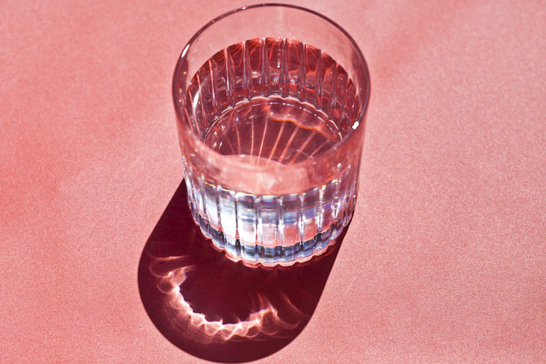 Glass of water against pink background