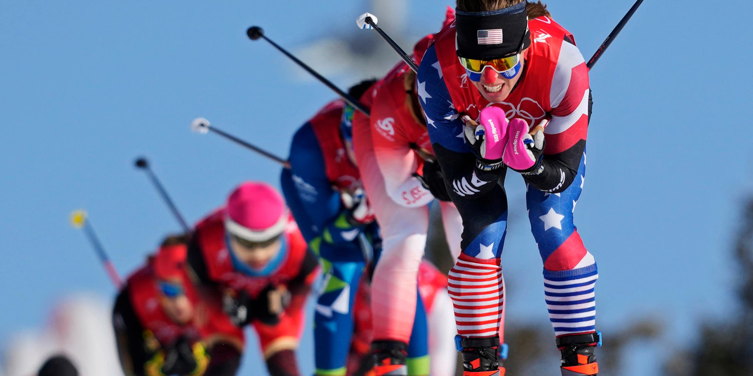 A row of female skiers races down a slope