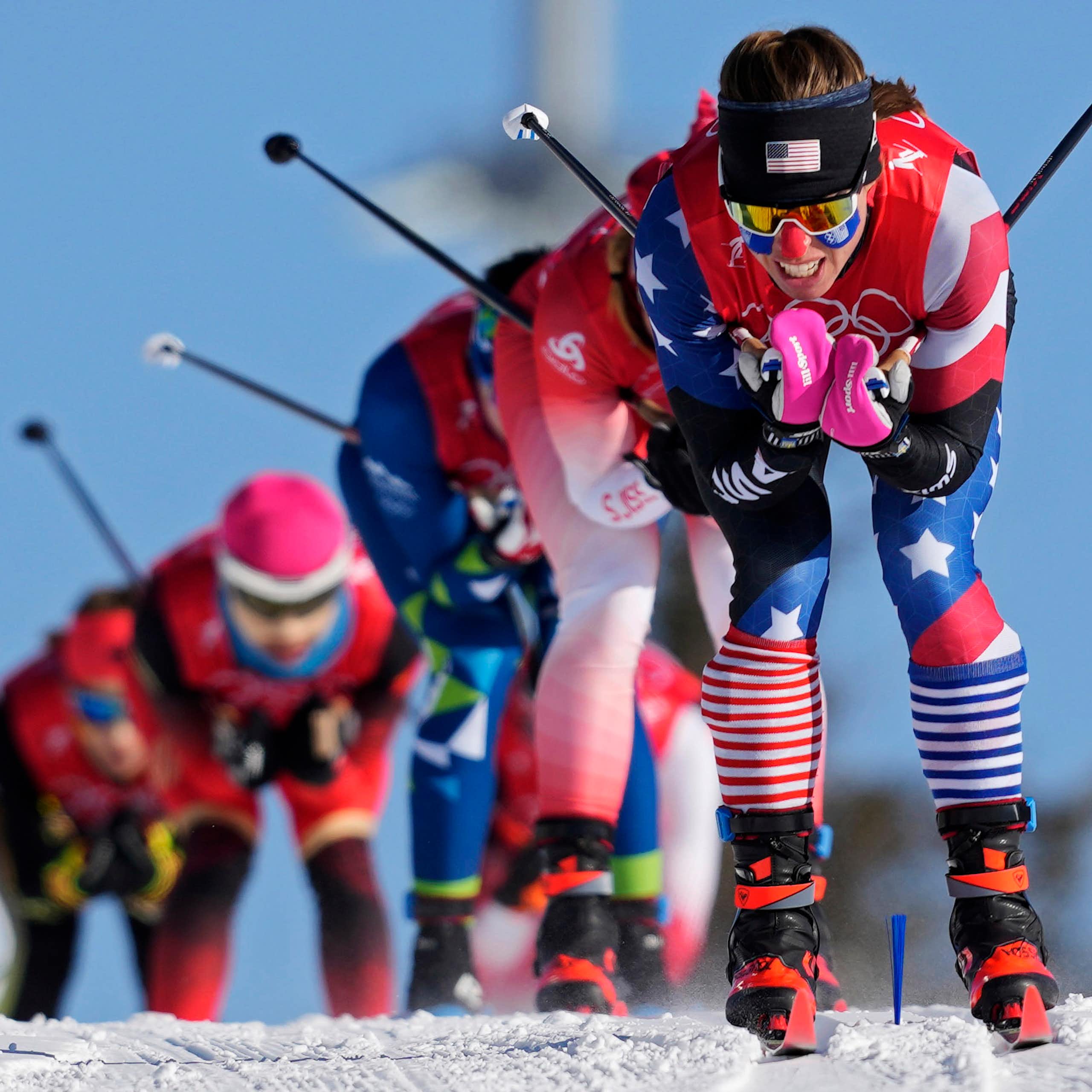 A row of female skiers races down a slope