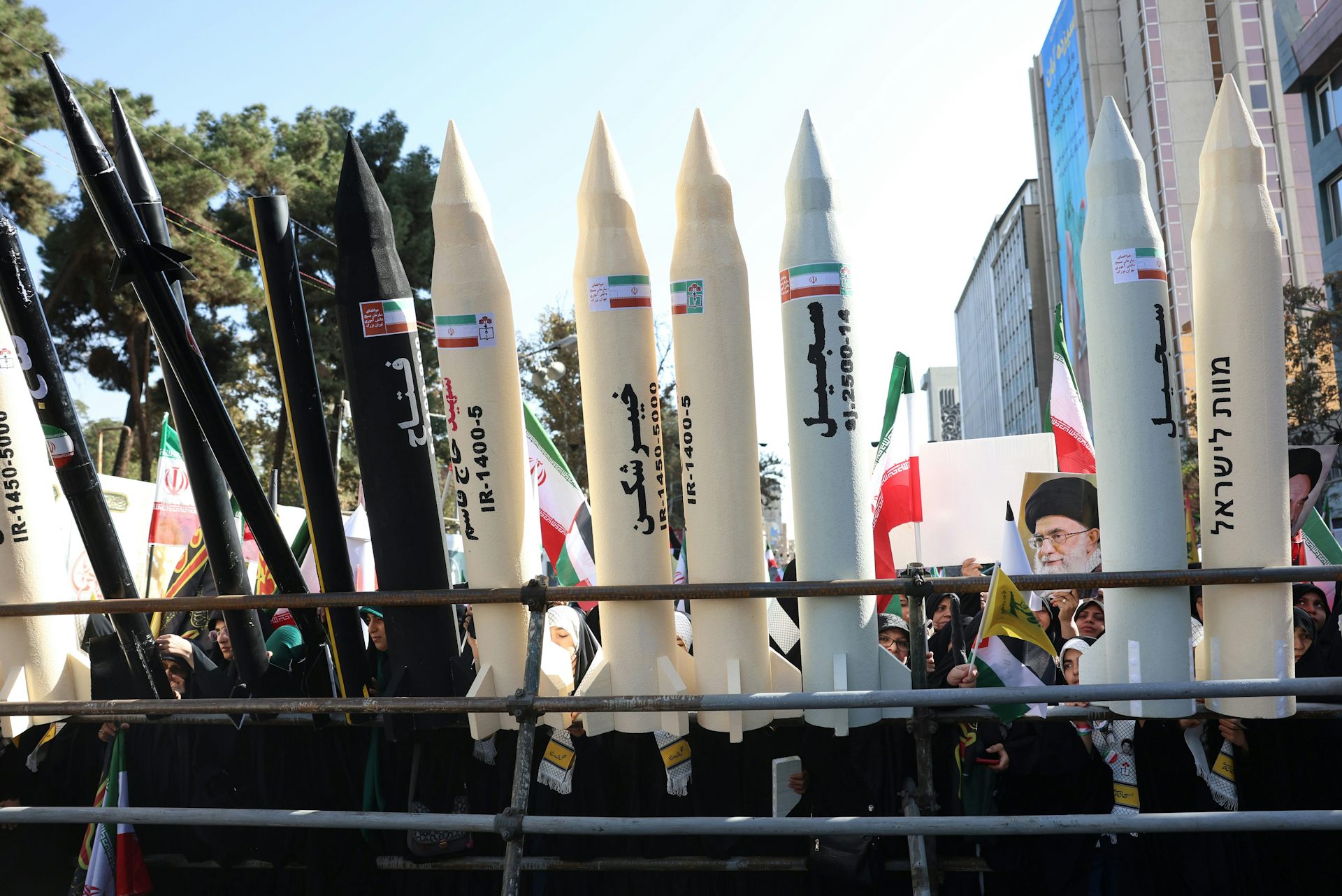 Iranians display a portrait of Ali Khamenei and mock missiles during an anti-US rally.