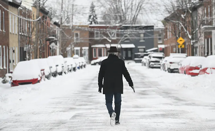 Un hombre visto desde atrás caminando por una calle nevada durante el día