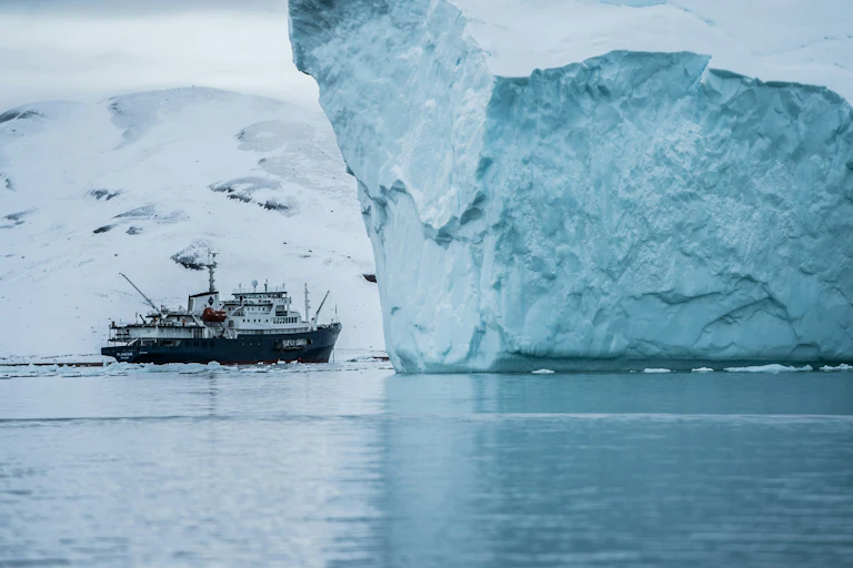 A ship sails passed an iceberg