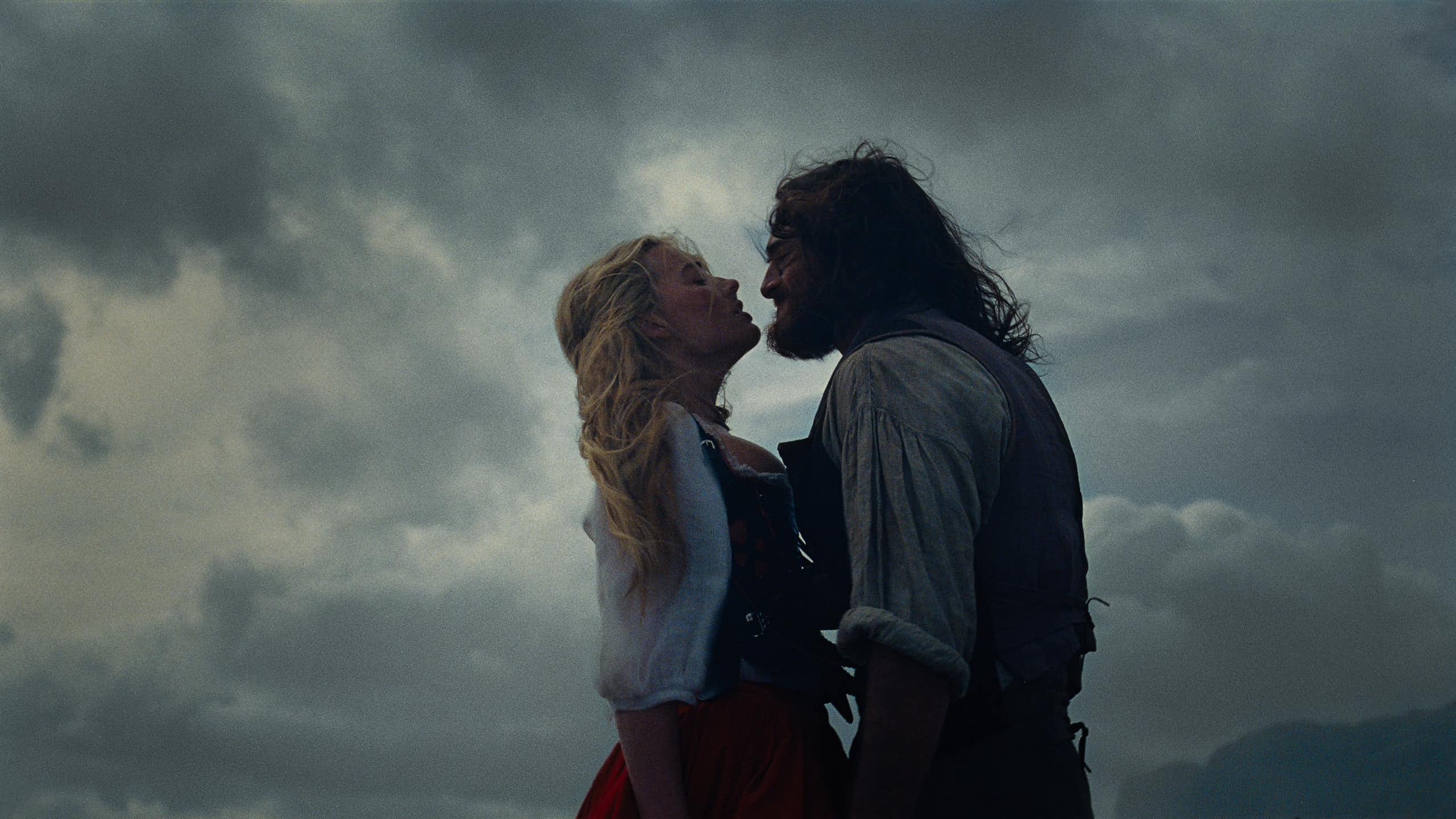 a brooding couple, a blonde woman and a long-haired man, against a stormy sky