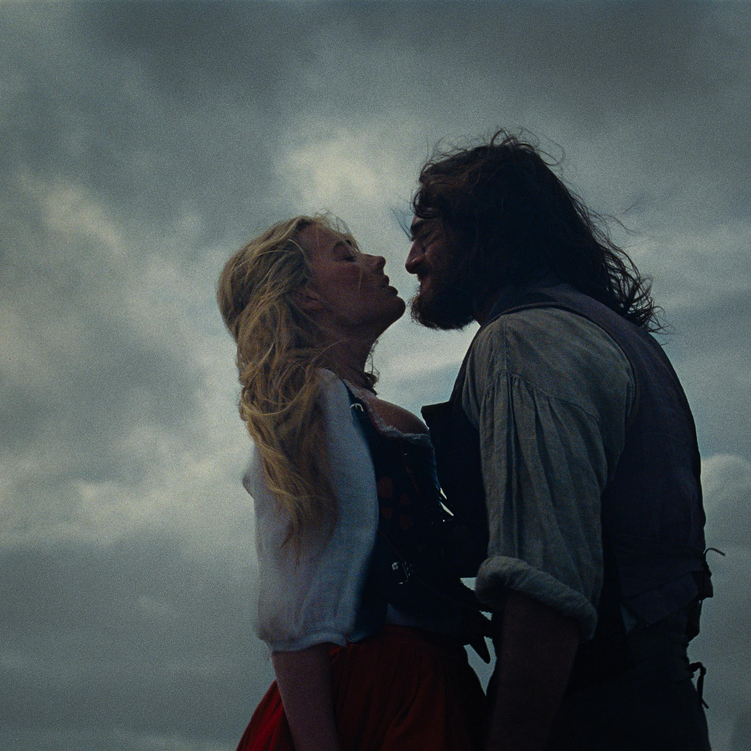 a brooding couple, a blonde woman and a long-haired man, against a stormy sky