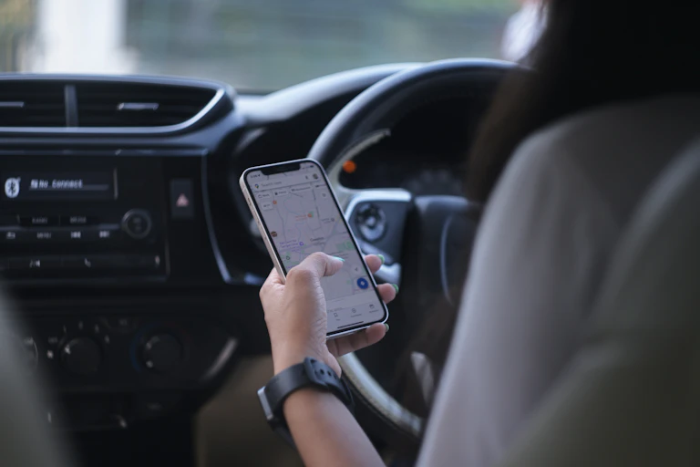 A woman uses her phone to view a map while driving.