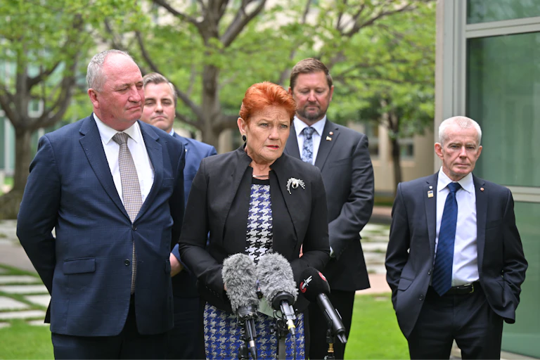 People in suits address the media outside Parliament House
